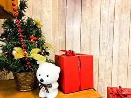 pequeño y lindo oso polar bajo el elegante y hermoso árbol de navidad de año nuevo. caja roja de regalo y decoración navideña de año nuevo foto