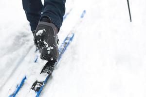 Feet of a skier in ski boots on cross-country skis. Walking in the snow, winter sports, healthy lifestyle. Close-up, copyspace photo