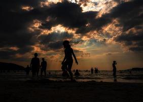 Silhouettes of people playing in the sea at a public beach photo