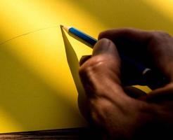 Human's hand holding pencil to write on the paper in shadow photo