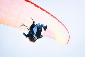 Underneath view instructor with tourist do paragliding in tandem while filming experience in clear skies good weather conditions in winter Gudauri ski resort photo