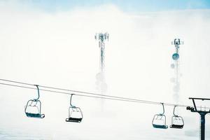 Gudauri ski chairlifts in clouds with signal antennas in background under mist and clouds photo