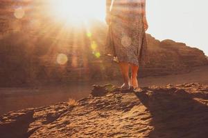 Close up oman barefoot walk on rocky Wadi rum cliffs surface on sunrise. Sunburst intentional filter blur