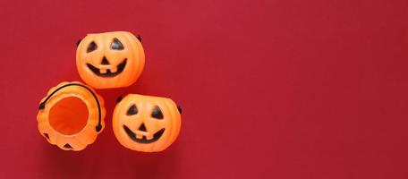 estilo plano del concepto de fiesta de halloween con calabazas de plástico decorativas sobre fondo rojo, espacio de copia con estilo de banner para texto y plantilla foto