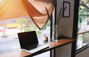 trabajo desde el concepto de casa, computadora portátil en una mesa de madera decorada con plantas en una habitación acogedora, trabajando de forma remota foto