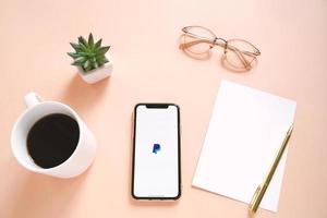 Flat lay of workspace desk and Apple iPhone XS with Paypal application on the screen. PayPal is an online electronic payment system photo