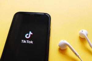 Flat lay of iPhone XS showing Tik Tok application on screen with earphones, Tik tok is popular social media network and entertainment photo