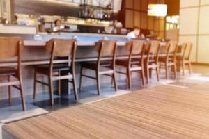 tablero de madera vacío en la parte superior de la mesa frente a un fondo borroso de café o restaurante, para exhibición y maqueta o productos de montaje foto