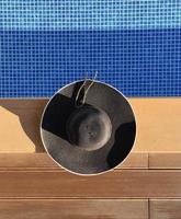 Top view of black panama hat on swimming pool, vacation and fashion concept photo