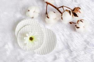 Cotton facial pads for removal makeup with natural cotton flowers on white fur background, hygiene and healthy care lifestyle photo