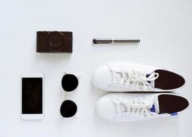 disposición plana de artículos de viaje, zapatillas y accesorios con smartphone sobre fondo blanco, concepto de moda y estilo de vida foto