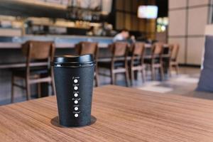 Take away coffee cup on wooden table in modern cafe or restaurant background, mock up concept photo