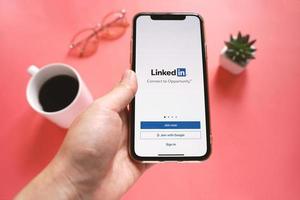 vista superior de la mano que sostiene el iphone xs de Apple con la aplicación Linkedin en la pantalla. Linkedin es un servicio de redes sociales orientado a los negocios. foto