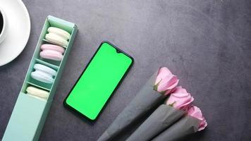 Pink roses and macaroons on table with smartphone with green screen video