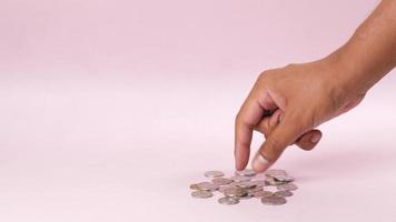 Loose coins on isolated background picked up one by one with hand video