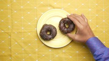 dos pequeños donuts de chocolate en la superficie amarilla video