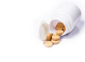 Medical pills spill out of a white jar on an isolated on white background photo