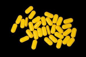 Medical orange pills on isolated on black background photo