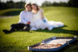 alegre pareja de jóvenes recién casados divirtiéndose recién casados con pizza foto