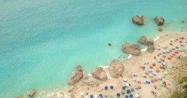 luftaufnahme des fantastischen idyllischen strandes mit bunten sonnenschirmen, sonnenliegen und sonnenbadenden und schwimmenden menschen. video