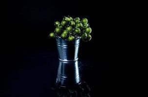 aluminum ice bucket laid in wait for use. stainless multi-colored bucket with green blue berries in ice photo