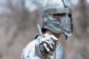 noble guerrero. retrato de un guerrero medieval o caballero con armadura y casco con escudo y espada posando foto