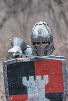 noble guerrero. retrato de un guerrero medieval o caballero con armadura y casco con escudo y espada posando foto