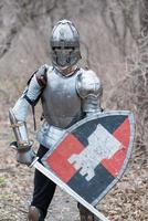 noble guerrero. retrato de un guerrero medieval o caballero con armadura y casco con escudo y espada posando foto