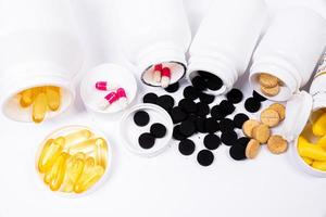 Medical pills spill out of a white jar on an isolated on white background photo