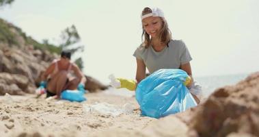 Mother And Daughter Collecting Trash On The Beach video