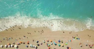 vue aérienne de la magnifique plage avec des parasols colorés et des personnes se relaxant et nageant dans l'eau claire de la mer méditerranée par une journée ensoleillée. video