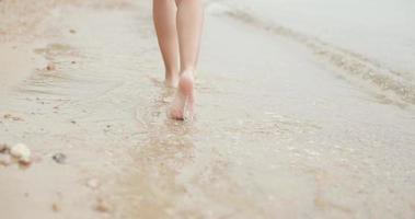 el primer plano de las piernas de una adolescente está caminando por la playa de arena vacía. video