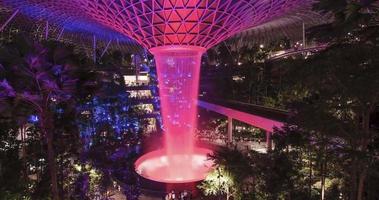 Zeitrafferansicht des Indoor-Wasserfalls im Juwel Changi, während ein Wirbelwasserfall mit Licht beleuchtet ist, tropischer Regenwald im Juwel video