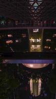 vertical timelapse view of indoor waterfall at The Jewel Changi while a vortex waterfall with light illuminated,indoor tropical rainforest in Jewel video