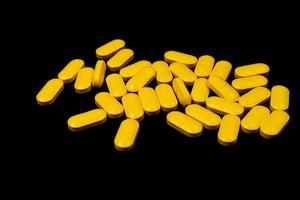 Medical orange pills on isolated on black background photo