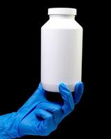 Medical pills in white jar on an isolated black background with reflection in hand photo