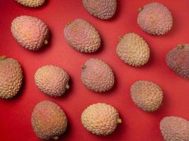 Lychee on the table. Chinese plum on a red background. Ripe fruit from Asia. photo