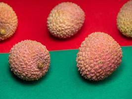 Lychee on the table. Chinese plum on a red -green background. Ripe fruit from Asia. Delicious, juicy product. photo