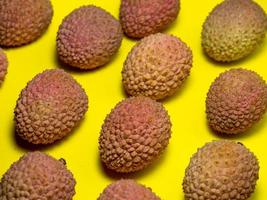 Lychee on the table. Chinese plum on a yellow background. Ripe fruit from Asia. photo