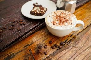 Hot cappuccino in white cup with wooden background,coffee is a popular drink all over the world. photo