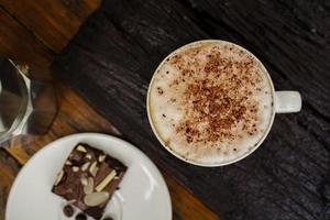 capuchino caliente en taza blanca con fondo de madera, el café es una bebida popular en todo el mundo. foto