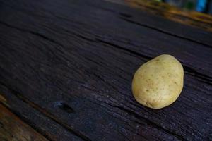 Raw potato diet.  Fresh potatoes on wooden floor . Space for messages . Raw potatoes that can be used in many dishes. photo