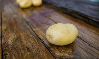 Raw potato diet.  Fresh potatoes on wooden floor . Space for messages . Raw potatoes that can be used in many dishes. photo