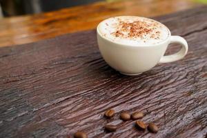 capuchino caliente en taza blanca con fondo de madera, el café es una bebida popular en todo el mundo. foto