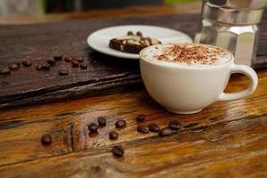 Hot cappuccino in white cup with wooden background,coffee is a popular drink all over the world. photo