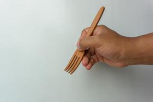 Hand holding wooden spoon and fork isolated on white background photo