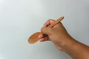 Hand holding wooden spoon and fork isolated on white background photo