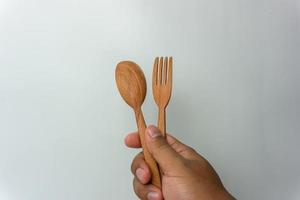 Hand holding wooden spoon and fork isolated on white background photo