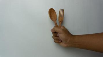 Hand holding wooden spoon and fork isolated on white background photo