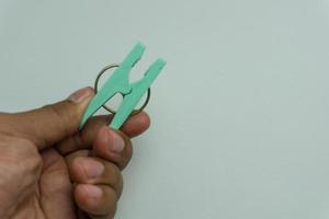 hand holding green clothes peg or clothes pin isolated on white backround photo